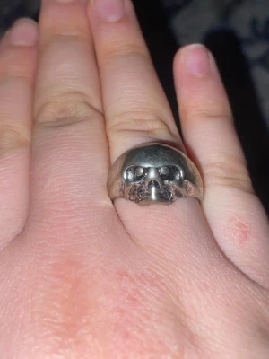 Silvrig ring med Vecna huvud på  - Cool Stranger Things ring i silverfärgad metall med ett detaljerat vecna huvud framtill. Ringen har en rundad form och är ganska chunky, vilket gör den till ett riktigt statement piece. Perfekt för dig som gillar edgy accessoarer och vill sticka ut.