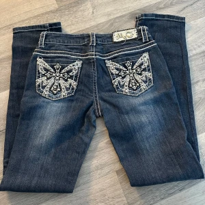 Mörkblå jeans med broderade bakfickor från Miss Chic - Snygga mörkblå jeans från Miss Chic med unika broderade detaljer på bakfickorna. Jeansen har en klassisk femficksdesign och en med dragkedja . Längden är ungefär 106cm. Perfekta för dig som vill ha något extra i garderoben! Och det är vintage kom med bud 🥳 säljer den för att den var för lång för mig som är 152 hade säkert passat dig perfekt som är 160-170 skulle jag gissa 😅