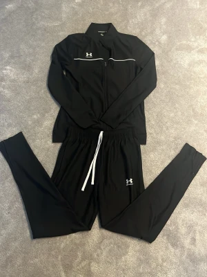 Svarta Under Armour träningskläder - Träningssett från under armour. Jätte bra skick och går även att köpa en av plaggen skicka ett dm! Super snyggt träningssett perfekt för sport och gym!