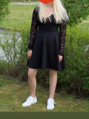 Svart spetsklänning från Goddiva - Supersnygg svart klänning från Goddiva med långärmade spetsärmar och v-ringad spets upptill. Klänningen ör kort och  har dragkedja i ryggen. Storlek 40, använt 1 gång 
