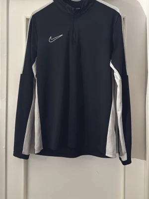 Svart Nike Dri-Fit träningströja Storlek M - Nike Dri-Fit träningströja i svart med vita ränder längs ärmarna och broderad logga på bröstet. Tröjan har quarter-zip framtill och är tillverkad i ett syntetmaterial som andas. Menad för dom som tar sport och aktivitet seriöst. Retail priset är 549 men säljer för 350 men priset går att pruta. Hör av er 👌🏼