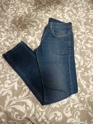 Levi's 511 Skinny Jeans Blå W31 L32 - Säljer ett par Levi's 511 skinny jeans i klassisk blå färg. Modellen har smal passform och raka ben, med fem fickor och snygga slitningar. Materialet är slitstarkt jeans och midjan är normal. Perfekt för dig som gillar en modern och stilren look.