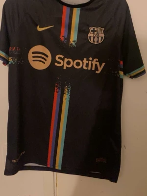 Barcelona Lewandowski matchtröja - Säljer en svart FC Barcelona matchtröja från Nike med Lewandowski och nummer 9 på ryggen. Tröjan har färgglada ränder framtill, Spotify-logga och klubbmärke på bröstet. Tillverkad i polyester och perfekt för fotboll eller att bära som supporter.