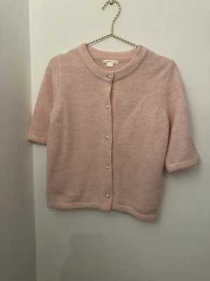 Ljusrosa kofta med pärlknappar - Supersöt ljusrosa kofta från Gina tricot med pärlknappar framtill. Koftan är stickad i mjukt material och har halvlånga ärmar samt rund halsringning. Perfekt att slänga över en topp för en gullig och chill look.