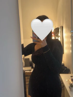 Svart tight klänning med slits - Säljer en svart, tight och kort klänning med lång ärm och slits på ena sidan. Klänningen har en rundad urringning och sitter figurnära