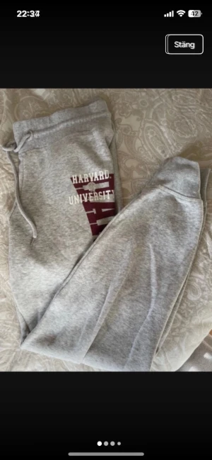 Grå Harvard University mjukisbyxor - Grå mjukisbyxor med tryck i vinrött och vitt från Harvard University. Byxorna har resår och snörning i midjan samt muddar vid bensluten. Perfekta för chill dagar eller när du vill ha det extra bekvämt.