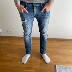 Blå Replay jeans med slitningar - Snygga blå jeans från Replay i modell med smal passform och slitna detaljer på låret. Jeansen har klassisk femficksdesign, normal midja och är tillverkade i bomull. Perfekta för dig som gillar en avslappnad men trendig look. Nypris: 2000kr. Pris kan diskuteras?