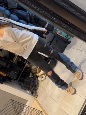 Svarta bootcut jeans med blå kilar - Unika svarta jeans med slitna detaljer och blå jeanskilar längst ner på benen som ger en bootcut-look. Byxorna har låg midja och är tillverkade i stretchigt jeans tyg.skriv för mer info och bilder🥰