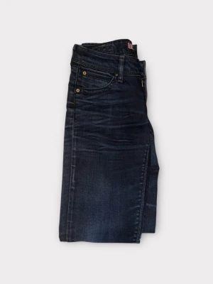 Levi's 571 mörkblå slim fit jeans - Säljer ett par Levi's 571 jeans i mörkblå tvätt med slim fit passform. Klassisk femficksdesign, guldfärgade nitar och Levi's röda logotagg på bakfickan. Jeansen är tillverkade i stretchigt denim för extra komfort och har en modern, smal siluett.