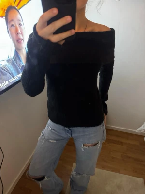 Svart offshoulder stickad tröja - Säljer en svart stickad tröja med offshoulder-modell och lång ärm. Tröjan är ribbstickad och sitter snyggt figurnära. Perfekt för dig som vill ha en stilren men ändå trendig look.