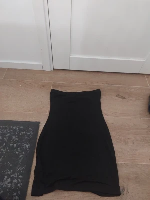 Svart tight klänning från SHEIN XS - Säljer en svart, tight klänningl från SHEIN i storlek XS. Klänningen  är enkel och rak i modellen, med en kort längd som sitter snyggt på kroppen. Perfekt för dig som gillar minimalistisk stil.