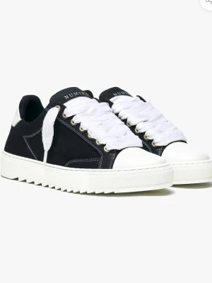 Svarta sneakers med vita detaljer - Söker efter ett par skor