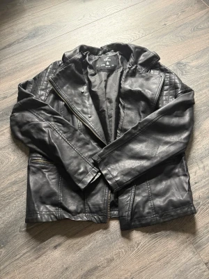 Svart skinnjacka med quiltade detaljer - Säljer en svart skinnjacka från YD!. Jackan har quiltade partier på axlar och rygg, dragkedjor vid fickorna och en klassisk krage. Snygg bikerstil som passar perfekt till jeans och boots.