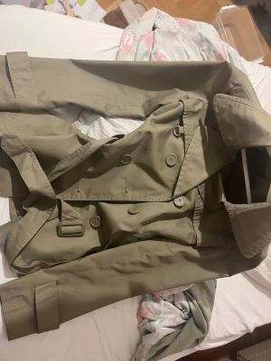 Beige trenchcoat från Vero Moda - Säljer en snygg beige trenchcoat från Vero Moda i storlek S. Jackan har dubbelknäppning, bälte i midjan och klassisk krage. Tillverkad i ett slätt material som känns lätt och stilrent. Perfekt för dig som vill ha en tidlös och trendig jacka.