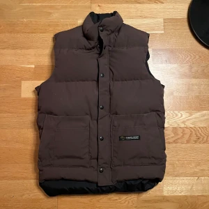 Vintage Canada Goose Väst - En vintage Canada Goose väst köpt i New York under tidigt 2000-tal. Västenr mörk brun och har inga märkbara defekter.