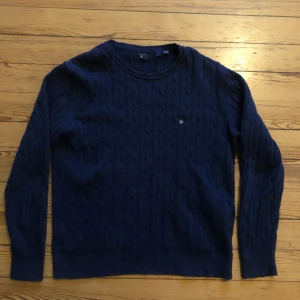 Mörkblå stickad tröja från Gant - Säljer en kabelstickad Gant tröja i storlek 170. Tröjan är i bra skick!