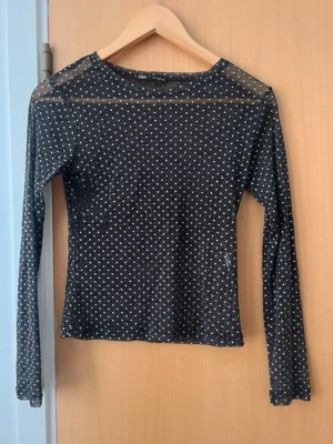 Prickig topp genomskinlig  - Svart mesh topp från Zara med vita prickar och lång ärm. Toppen är genomskinlig och har en tight passform, perfekt att styla lager på lager. Materialet är syntet och toppen har en klassisk rund halsringning.