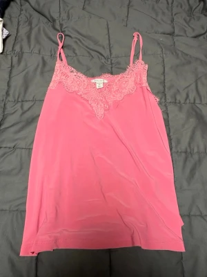Rosa spetslinne från Amisu XS - Säljer en rosa linne från Amisu i storlek XS. Linnet har tunna axelband och v-ringad spetskant framtill, linnet har ett sträck fram på linnet som inte går att få bort men de är inget man tänker på när man har det på sig 