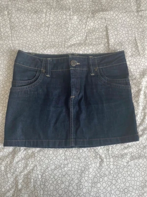 Mörkblå jeanskjol från ONLY - Säljer en mörkblå jeanskjol från ONLY i klassisk modell med fem fickor, bälteshällor och kontrastsömmar. Kjolen är kort och har knapp- och dragkedjestängning framtill. Perfekt till sneakers eller boots för en cool look. Tar gärna emot bud och skriv om ni har frågor💕😊