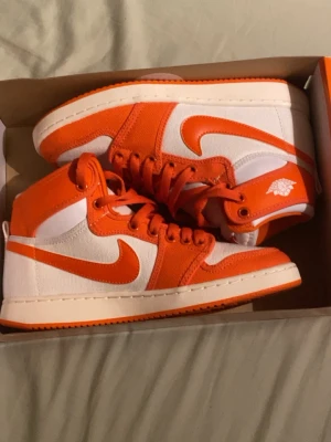 HELT NYA Jordan AJKO 1 Mid ”Rush Orange” – Strl 38 - Säljer ett par helt oanvända Jordan AJKO 1 i den snygga ”Rush Orange”-färgen. Skorna är helt nya, aldrig använda och har fortfarande kvar plasttaggen/plomberingen från butik. AJKO-modellen kännetecknas av sitt slitstarka canvas-material vilket ger en schysst retrokänsla och gör dem perfekta för våren och sommaren. • Skick: 10/10 (Helt nya / DS) • Storlek: 38 (5.5Y) • Tillbehör: Originalbox medföljer självklart • Info: Taggen sitter kvar på skorna 