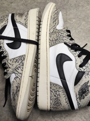 Nike Air Jordan 1 High Elephant Print – stl 42,5 - Nike Air Jordan 1 High i den klassiska svart/vita färgsättningen med elephant print-detaljer. Skorna är använda men i bra skick. Lädret är fint överlag med normalt bruksslitage, sulorna har kvar bra mönster och inget som påverkar funktion eller passform. Innersidor och hälpartier hela. Ett par som funkar bra både att bära direkt eller som bas för rotation. Storlek 42,5. Se bilder för detaljer och skick.