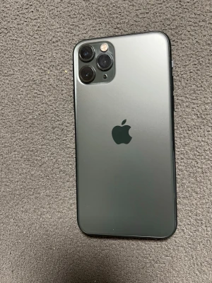 iPhone 11 Pro grön med skal - Snygg iPhone 11 Pro i matt grön färg med tre kameror på baksidan och stilren design. Baksidan är i glas och ramen i metall. Medföljer ett svart skal från iDeal of Sweden med krokodilstruktur och gulddetalj. batteri 100%