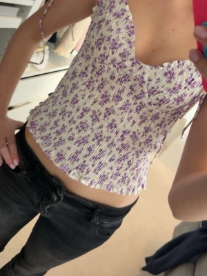 Ljuslila blommig smockad linnetopp - Supersöt linnetopp med smockad passform och tunna knytband. Nästan aldrig använd så i superbra skick! Skicka gärna prisförslag och skriv om ni har frågor 