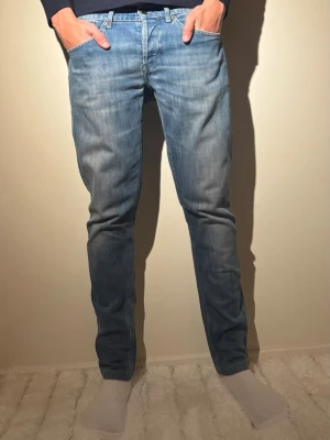 Dondup George jeans - Snygga och stilrena Dondup jeans – modell George (Skinny Fit) i klassisk blå tvätt. Ett premiumplagg från Italien med bra passform och fina detaljer.  ✔️ Märke: Dondup✔️ Modell: George✔️ Passform: Skinny fit✔️ Storlek: 34✔️ Färg: Blå denim✔️ Skick: Bra begagnat skick✔️   Jeansen har normal midja, smal benform och funkar perfekt både till vardag och mer uppklädda outfits. Tidlös tvätt som aldrig går ur stil.  Nypris för Dondup jeans ligger högt – perfekt chans.