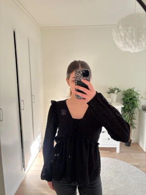 Svart blus med v-ringning och volang - Säljer en svart blus med v-ringning och volangdetaljer. Säljer denna då den aldrig kommer till användning! 🩷Storlek 170, Gina Young 