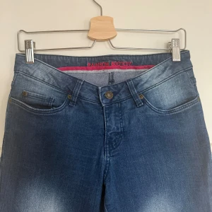 Blå bootcut jeans från Rainbow - Jeansen ben har sprättats upp för att bli längre. Midjemått: 39,5 cm. Innerbenslängd: 81 cm. Jeansen passar en storlek XS/S. Hör av dig om du har några frågor!!