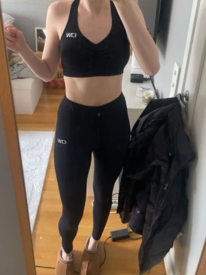 Svart träningsset från ICIW - Säljer ett svart träningsset från ICIW med sport-bh och tights. Sport-bhn har korsade axelband i ryggen och tightsen är höga i midjan med scrunch. Båda plaggen är i stretchigt material som passar perfekt för gym eller yoga.