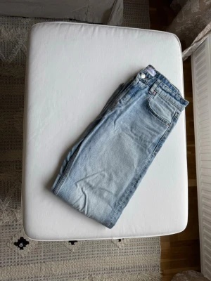 Ljusblå raka jeans - Säljer ett par ljusblå jeans med klassisk femficksdesign och raka ben. Jeansen har normalhög midja och är tillverkade i denim. Perfekta för en avslappnad och trendig look.