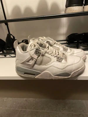Vita Air Jordan 4 Retro sneakers - Säljer ett par vita Air Jordan 4 Retro sneakers med grå detaljer och meshpaneler på sidorna. Använda.