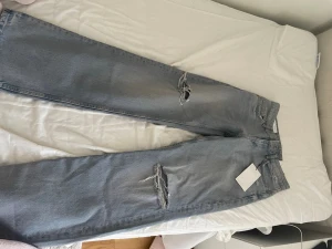 populära Ljusblå ripped jeans från Zara - Säljer ett par nya ljusblå jeans från zara med wide leg och slitna detaljer på båda benen. Jeansen har klassisk femficksdesign och låg midja. Jag säljer för att de var för små. Lapparna finns kvar.