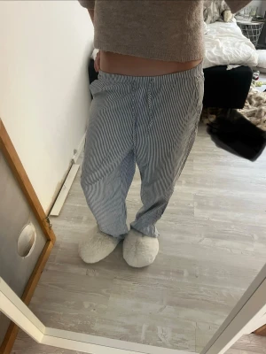 Randiga pyjamasbyxor i bomull - Mysiga pyjamasbyxor med tunna blå och vita ränder. Byxorna har resår i midjan och är tillverkade i mjuk bomull, perfekta för chill hemma. Klassisk rak passform och avslappnad stil.