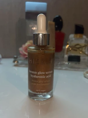 Hickap Bronze Glow Serum - Bronze Glow Serum från Hickap med hyaluronsyra ger huden en fräsch, solkysst lyster. Serumet är bronsfärgat och kommer i en glasflaska med pipett. 100% veganskt och passar alla hudtyper. Perfekt för dig som vill ha glow och återfuktning i ett steg. Helt ny och oanvänd. 