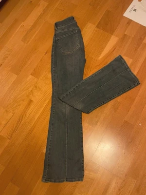 Blå jeans med fickor från Nelly - Säljer ett par blå jeans från Nelly med boot cut ben och markerade sömmar framtill. Jeansen har två stora fickor framtill och låg/mid midja. Klassisk blå denim som passar till det mesta. Materialet är bomullsdenim med lite stretch.