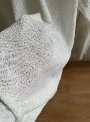 Vit stickad långärmad tröja från H&M - En enkel och stilren vit stickad tröja från H&M med rund halsringning och långa ärmar. Tröjan har en mjuk och lite grovstickad struktur, ribbade muddar vid hals och ärmslut samt en rak passform som är lätt att matcha med jeans eller kjol