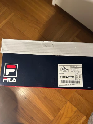 Fila Disruptor Premium vita sneakers - Fila Disruptor Premium sneakers i helvit med detaljer i marinblått och rött. Chunky design med platt sula och rund tå. Skorna har snörning och är tillverkade i syntetmaterial med Fila-logga på sidan och tungan. Perfekt för dig som gillar retrostil och streetwear. Strl i lager: 38, 39, 40.5 och 41.