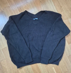 Svart stickad tröja från PS Fashion - Svart stickad tröja från PS Fashion i storlek 40. Tröjan har en v-ringad hals och grov ribbad struktur som ger en chill och klassisk vibe. Långärmad och perfekt för lager-på-lager under kyliga dagar. Enkel att matcha med jeans eller kjol.