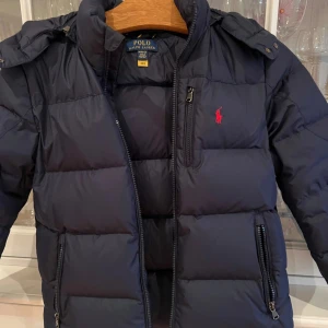 Vinterjacka 10-12 år Ralph Lauren - Mörkblå täckjacka Ralph Lauren. Varm. Mycket fint skick och väldigt sparsamt använd. Inköpt på Outlet i Barcelona förra säsongen. 10-12 år. Ena fickan går inte att stänga helt optimalt. Priset är diskuterbart. 