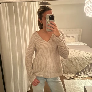 Beige stickad v-ringad tröja H&M - Beige stickad tröja från H&M med v-ringning och ribbade muddar. Tröjan har en avslappnad passform och långa ärmar. Enkel och stilren design som funkar till det mesta.