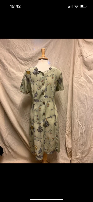 Blommig ljusgrön klänning  - 95 cm från axeln. 