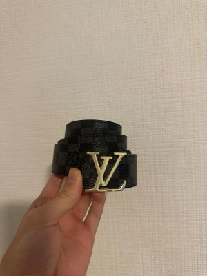 Svart rutigt bälte - Svart rutigt bälte med guld badge i storlek 110