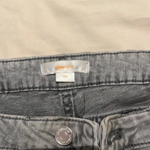 Grå jeans från Gina Tricot, utsvängda byxor  - Säljer ett par grå jeans från Gina Tricot, utsvängda/flare och lågmidjade. Byxorna har flera silverfärgade knappar framtill, klassiska fickor och bälteshällor. Sitter bra på mig men för långa. Lite smutsiga nerifrån men kan testa tvätta dom innan dom säljs annars får du dom billigare 