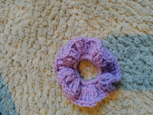 Ljuslila virkad scrunchie - Superfin ljuslila virkad scrunchie som ger en söt touch till din frisyr. Den är handgjord i mjukt garn och har ett fluffigt, voluminöst utseende. Perfekt för att piffa upp håret med lite färg och stil. Virkad av mig!