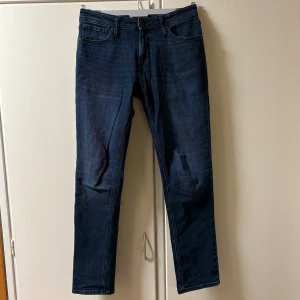 Jack & Jones Jeans - Snygga mörkblå jeans från Jack & Jones, modell Clark Regular. Endast använda 2-3 gånger. Nypris: 699kr, Skick 10/10. Perfekta för dig som gillar stilrena och tidlösa jeans. Passformen är enligt mig perfekt, slimmade men inte för tajta. Vid frågor eller funderingar är det bara att höra av sig.