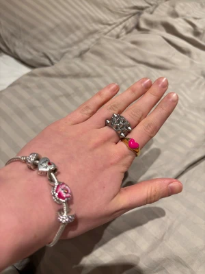 Guldring med rosa hjärta från Edblad - Snygg guldfärgad ring från Edblad med ett rosa hjärta framtill. Ringen har en rundad form och är tillverkad i metall med blank finish. Perfekt statement-piece för dig som gillar färg och lekfulla detaljer. Storlek 17.5