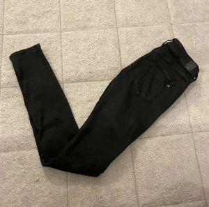 Svarta Replay jeans w28/32 - Snygga svarta Replay jeans med klassisk femficksdesign. Jeansen har en smal passform och är tillverkade i stretchigt jeansmaterial för extra komfort. Perfekta för dig som gillar en stilren och modern look.