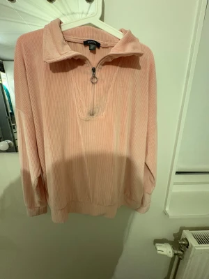 Ljusrosa manchestertröja från Esmara - Säljer en ljusrosa långärmad tröja från Esmara i mjuk manchester med ribbad struktur. Tröjan har en halv dragkedja med ringdetalj vid halsen och en loose passform. Perfekt för chill dagar och snygg att matcha med jeans eller mjukisbyxor.